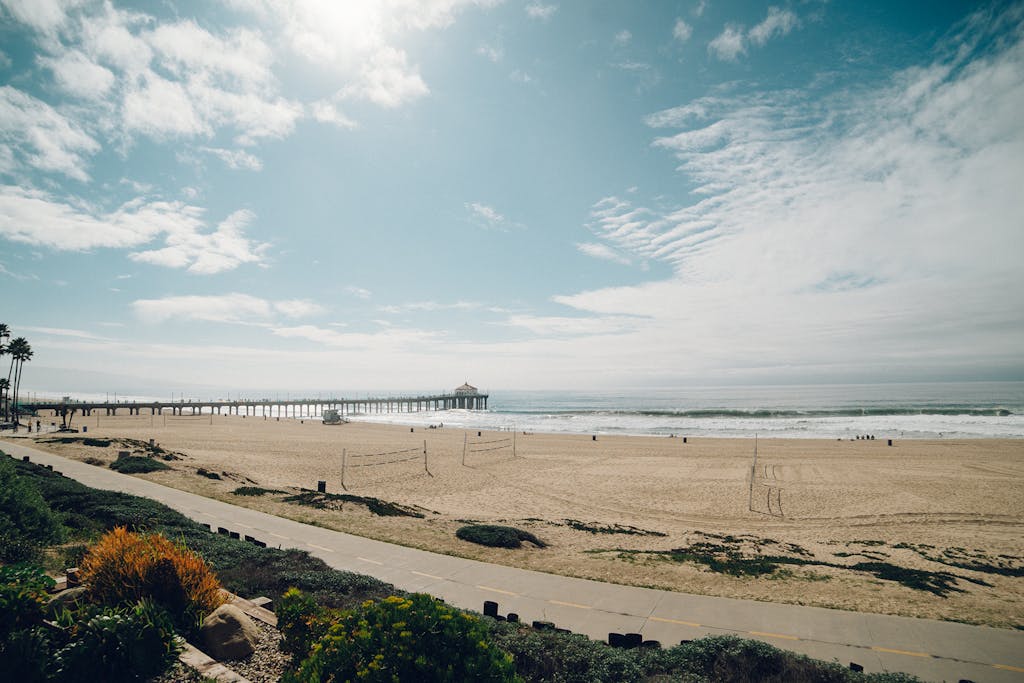 Breathtaking view of Manhattan Beach Pier with blue sky and sandy beach.